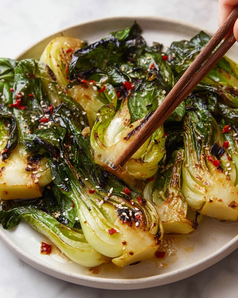 The dish shows five pieces of grilled baby bok choy arranged in a white plate, each piece having green leaves and light yellow-green stalks with charred, brown edges, and a shiny glaze on top. The bok choy layers reveal a texture of both soft leaves and crisp stalks. Sprinkled over the bok choy are white sesame seeds and a few red chili flakes. To the left, there is a white small bowl with a dark soy sauce next to brown chopsticks on a white marbled surface. In the top right corner, there is a small wooden bowl filled with white sesame seeds. photo taken with an iphone --ar 4:5 --v 7