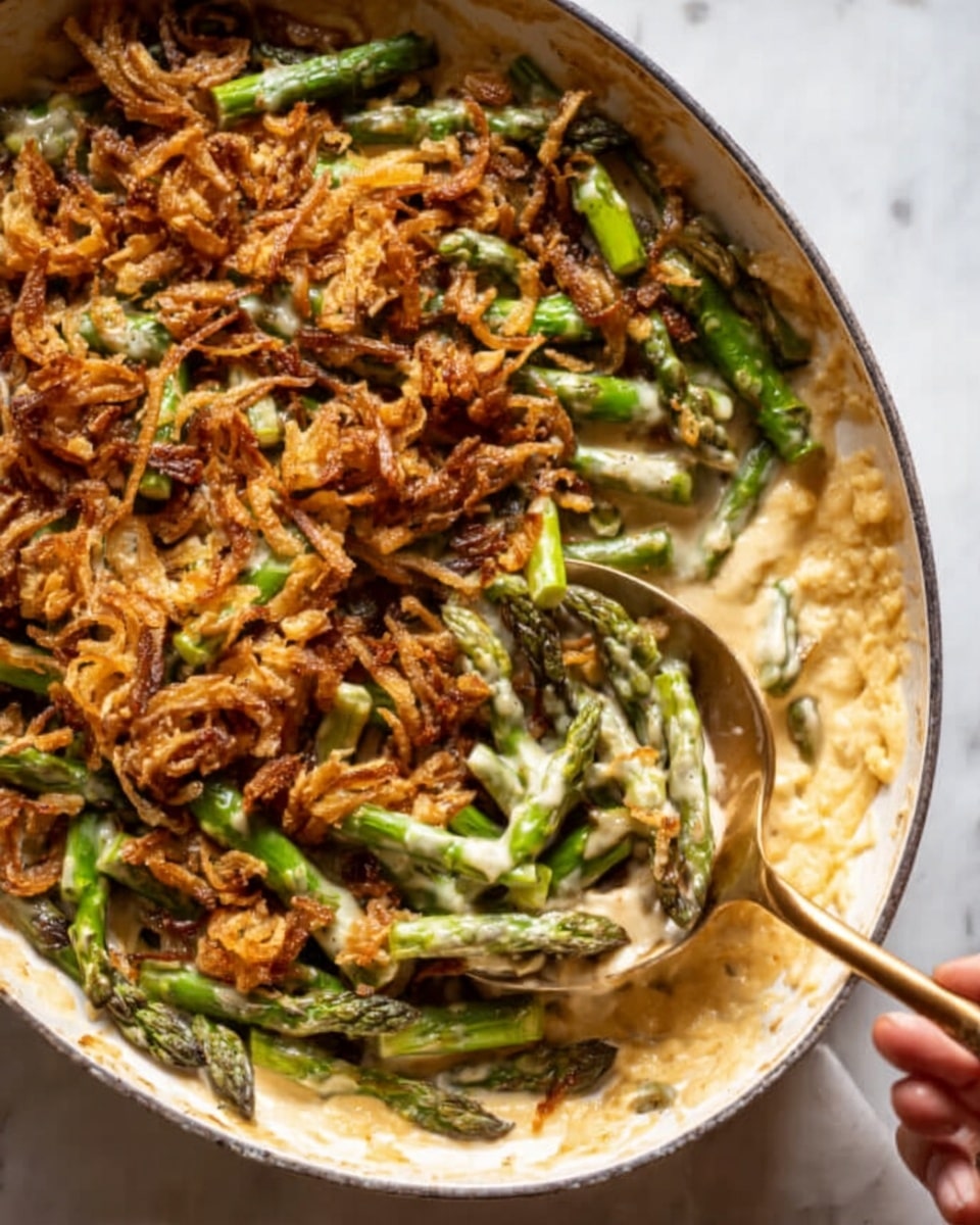 The image shows a black cast iron pan filled with creamy green beans and mushrooms coated in a thick beige sauce. The green beans are bright green, mixed with whole sautéed mushrooms. On top, there is a generous layer of crispy fried onion strips with a deep golden brown color and some white grated cheese sprinkled over everything. A large gold spoon is resting inside the pan, partly covered with sauce. The pan sits on a soft beige cloth on a white marbled surface and some fried onion strips are scattered nearby. Photo taken with an iphone --ar 4:5 --v 7