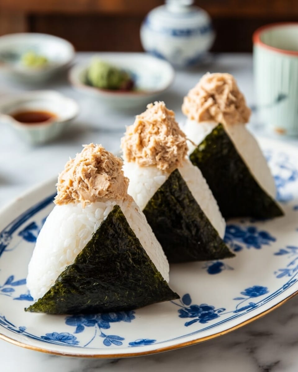 The image shows three triangular rice balls wrapped partially in dark green seaweed sheets, placed on a white plate. Each rice ball has a textured surface of white rice mixed with small black seeds or seasoning. The seaweed wraps around the lower half of each triangle, giving a sharp contrast between the white rice and the dark green color. One rice ball is held by a woman's hand with painted brown nails, positioned in the foreground, while the other two rest on the plate in the background. The plate sits on a white marbled surface. Photo taken with an iphone --ar 4:5 --v 7