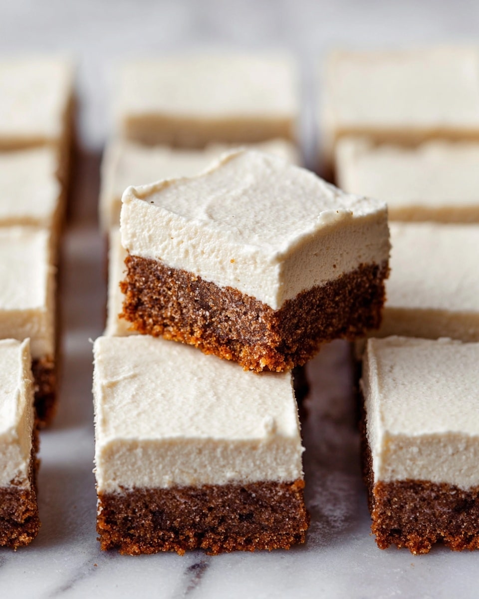 This image shows a stack of square dessert bars arranged on a white plate with a black rim, placed on a white marbled surface. Each bar has two visible layers: a thick bottom layer that is golden brown and looks soft and moist with a slightly crumbly texture, and a top layer that is creamy white, smooth, and slightly thick, resembling frosting or cream. One bar is placed on top of the stack, showing a bite taken out of it, which reveals the soft and dense inside of the brown layer and the creamy top layer clearly. The background is softly blurred with white and subtle light tones, keeping the focus on the dessert bars. photo taken with an iphone --ar 4:5 --v 7