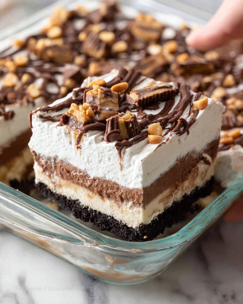 The image shows a dessert in a clear glass baking dish with four visible layers. The bottom layer is a dark, crumbly chocolate crust, followed by a light beige creamy layer. Above this is a thick, rich chocolate layer, and the top layer is fluffy white whipped cream decorated with a chocolate drizzle grid pattern. The whipped cream is also topped with small peanut butter cups, chopped peanut butter cups, small round peanut butter candies, and tiny chocolate chips. A piece has been cut out, revealing the layers clearly, and the dish is placed on a white marbled surface. photo taken with an iphone --ar 4:5 --v 7