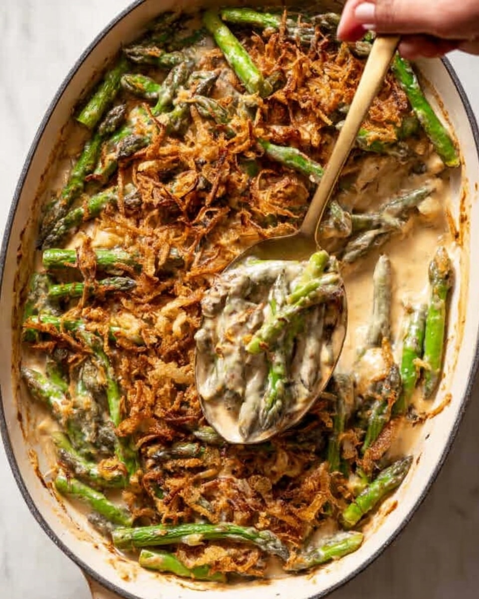 The dish is shown in a large white pan filled with multiple layers. The bottom layer is a creamy sauce with a light beige color, covering the whole base. On top of the sauce, there are bright green asparagus spears arranged in a scattered but even way. The top layer consists of a mix of golden brown, crispy fried onions spread across the asparagus and sauce. A woman's hand holds a gold spoon scooping a portion from the right side, revealing the creamy sauce and asparagus underneath. The pan is set on a white marbled surface. Photo taken with an iphone --ar 4:5 --v 7