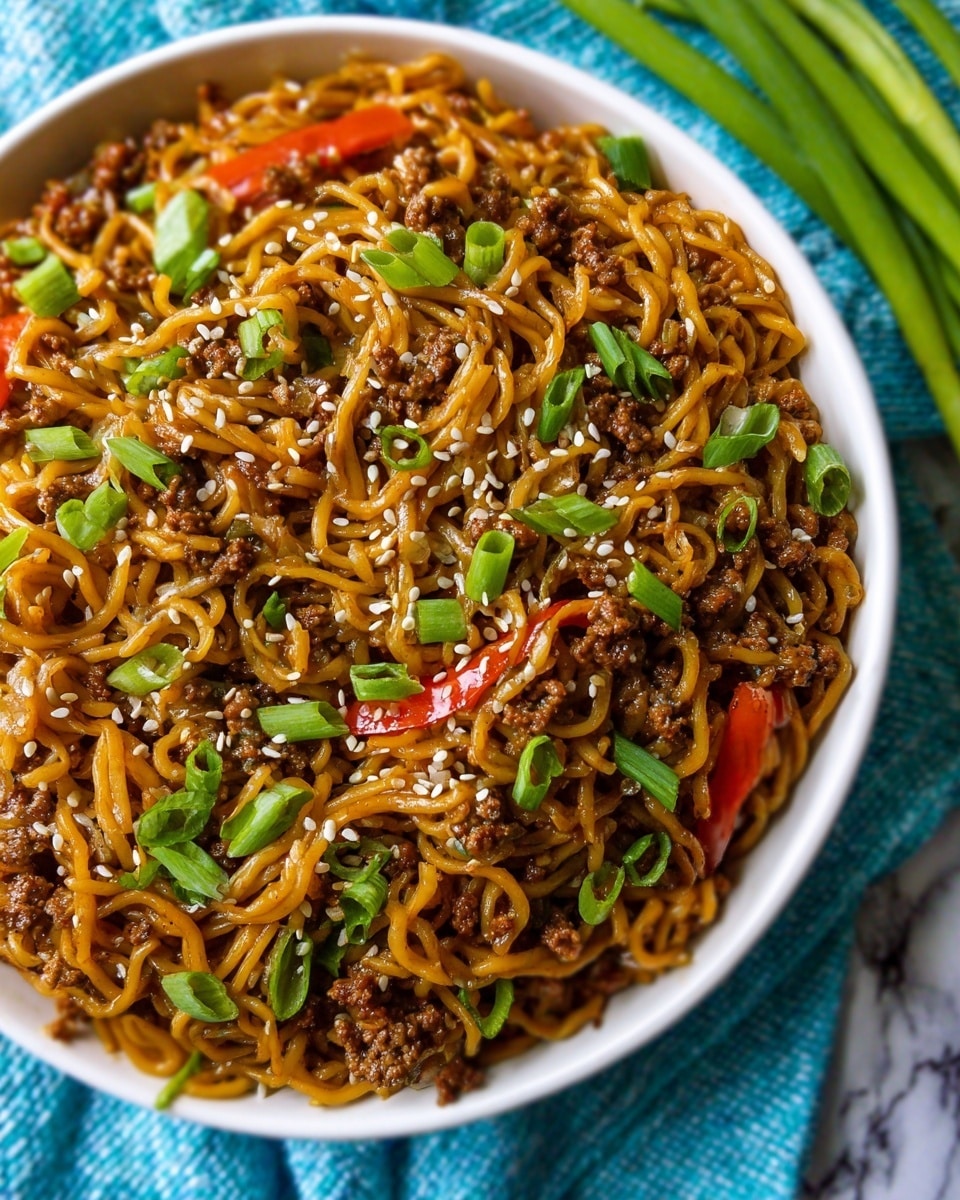 A close-up view of a white bowl filled with cooked noodles mixed evenly with small pieces of browned ground meat and thin slices of red bell peppers, topped with white sesame seeds scattered all over and bright green chopped spring onions that add a fresh pop of color. The noodles have a shiny, slightly oily texture, and the ingredients are well combined to create a layered look of twisted noodles, meat, and vegetables. The bowl sits on a blue textured cloth with a white marbled surface beneath, and a bunch of green onions lies nearby. Photo taken with an iphone --ar 4:5 --v 7