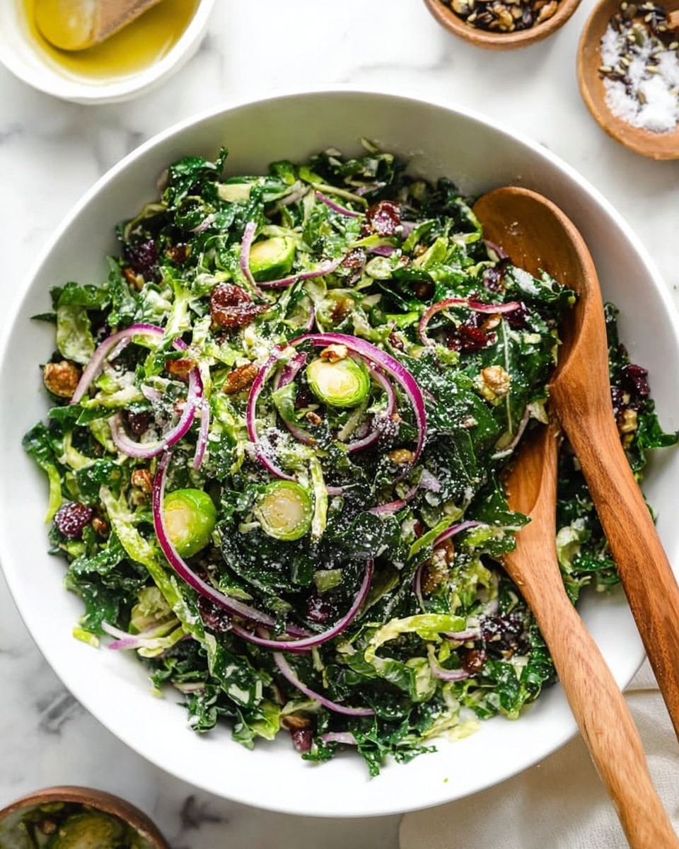 A large white bowl is filled with a fresh green salad that has about three main visual layers: a base of finely shredded dark green kale and bright green Brussels sprouts, mixed with thin, curved slices of pale purple-red onion spread evenly throughout, and scattered small dark red dried cranberries and light brown roasted pistachios. The salad has a light sprinkling of white grated cheese on top, adding a delicate texture. Two wooden salad spoons rest inside the bowl, partially mixing the ingredients. The bowl sits on a white marbled surface with small bowls of ingredients softly blurred around it. Photo taken with an iphone --ar 4:5 --v 7