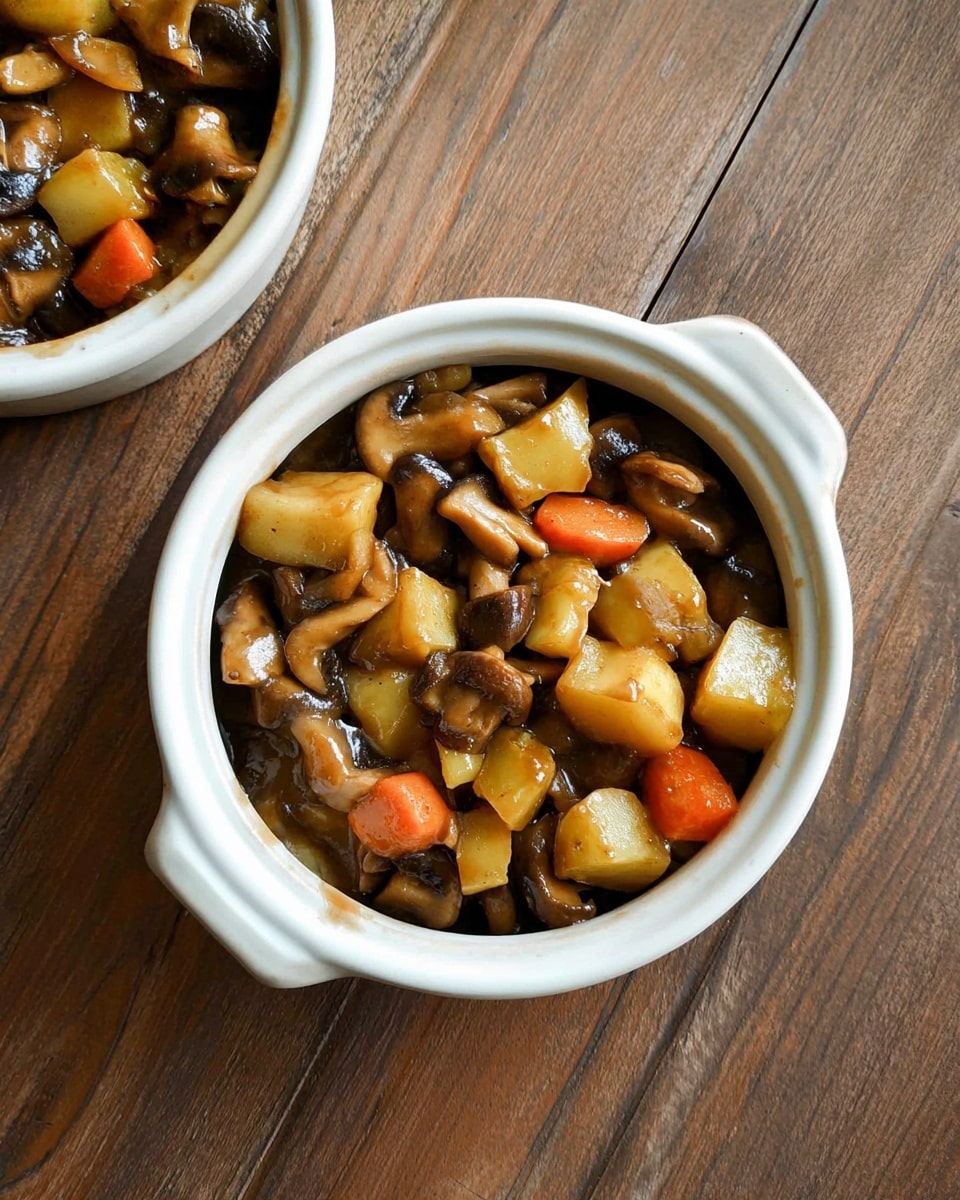 The image shows a round pot pie with a golden brown crust that has a slightly bumpy texture and small black pepper specks on top. The crust is thick and covers a white ceramic dish with handles on the side. A spoon is scooping out the pie, revealing the inside filled with chunks of brown mushrooms, orange carrots, and a few green herbs, with a juicy and hearty texture. A sprig of fresh green rosemary rests on the top right side of the crust. The dish is placed on a wooden surface with a light purple cloth peeking underneath. photo taken with an iphone --ar 4:5 --v 7