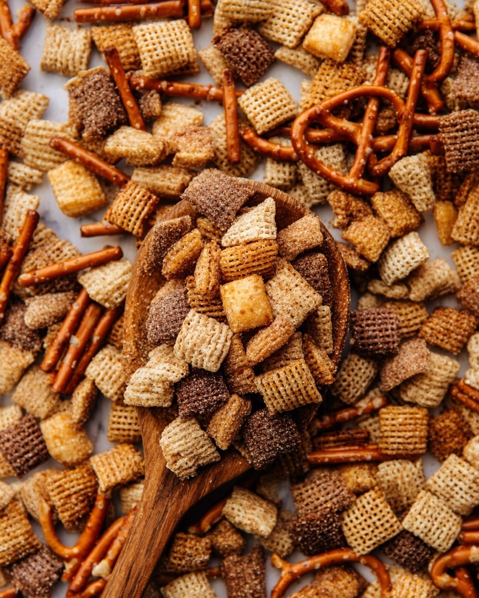 The image shows a close-up of a snack mix made of many small pieces, including square and rectangular cereal pieces in light brown and dark brown colors, round cereal loops in golden brown, thin pretzel sticks in a reddish-brown shade, and square cheese crackers in pale yellow. The snack mix is coated with a layer of cinnamon sugar that glistens on all the pieces, giving a sparkling effect. A wooden spoon filled with this mix is placed near the center and slightly towards the top right, resting on a spread of more snack mix on a white marbled texture. The colors are warm and earthy, with the texture showing the crunchiness of the cereal and pretzels, and the sugary coating adds a rough, grainy detail. photo taken with an iphone --ar 4:5 --v 7