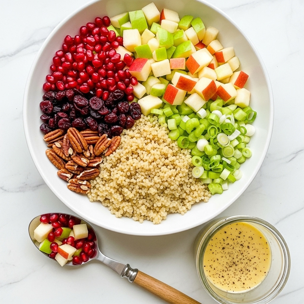 A white bowl filled with six different ingredients arranged in separate sections: light beige cooked quinoa with a soft texture in the center, bright red glossy pomegranate seeds on the top left, dark red dried cranberries next to the quinoa, light brown pecan halves below the cranberries, light green chopped celery and scallions on the right side, and small cubes of green and red apples mixed with light-colored pear pieces in the top right. Below the bowl on a white marbled surface, there is a silver spoon with a wooden handle holding some apple cubes and pomegranate seeds, and a small glass jar filled with a smooth, light yellow dressing speckled with black pepper. Photo taken with an iphone --ar 4:5 --v 7