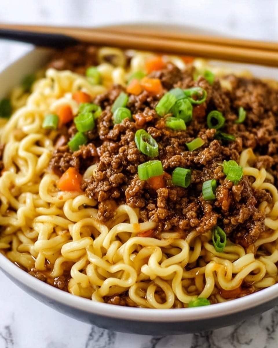A close-up view of a bowl filled with thick, wavy yellow noodles as the base layer, topped with a rich brown minced meat sauce layer scattered unevenly over the noodles. Small pieces of orange carrot slices and chopped green onions add bright color on top, with some green onion pieces focused near the center. A pair of light wooden chopsticks rest on the edge of the white bowl, resting on the noodles. The background shows a white marbled surface. photo taken with an iphone --ar 4:5 --v 7