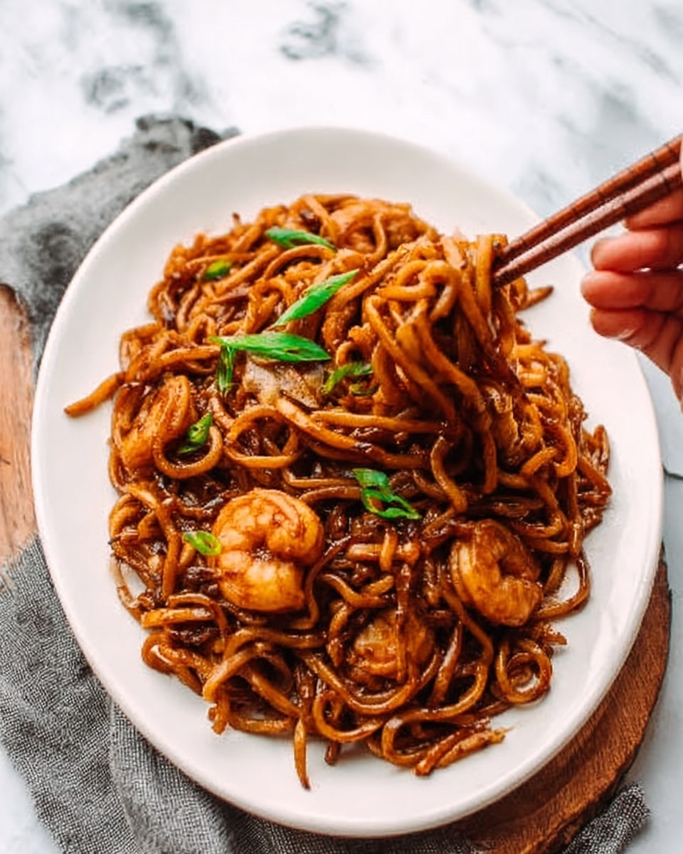 The image shows a white bowl filled with stir-fried udon noodles layered at the bottom, appearing thick and glossy with a dark brown sauce. On top of the noodles are medium-sized shrimp cooked to a light pink color, mixed with dark green leafy vegetables and small pieces of light brown onion. The dish looks shiny and coated with sauce, with some sesame seeds sprinkled lightly over the top. In the background, there are chopped green onions on a white plate and a small bowl of sesame seeds, all set on a white marbled surface. A woman’s hand holds wooden chopsticks above the bowl as if about to pick up the noodles. Photo taken with an iphone --ar 4:5 --v 7