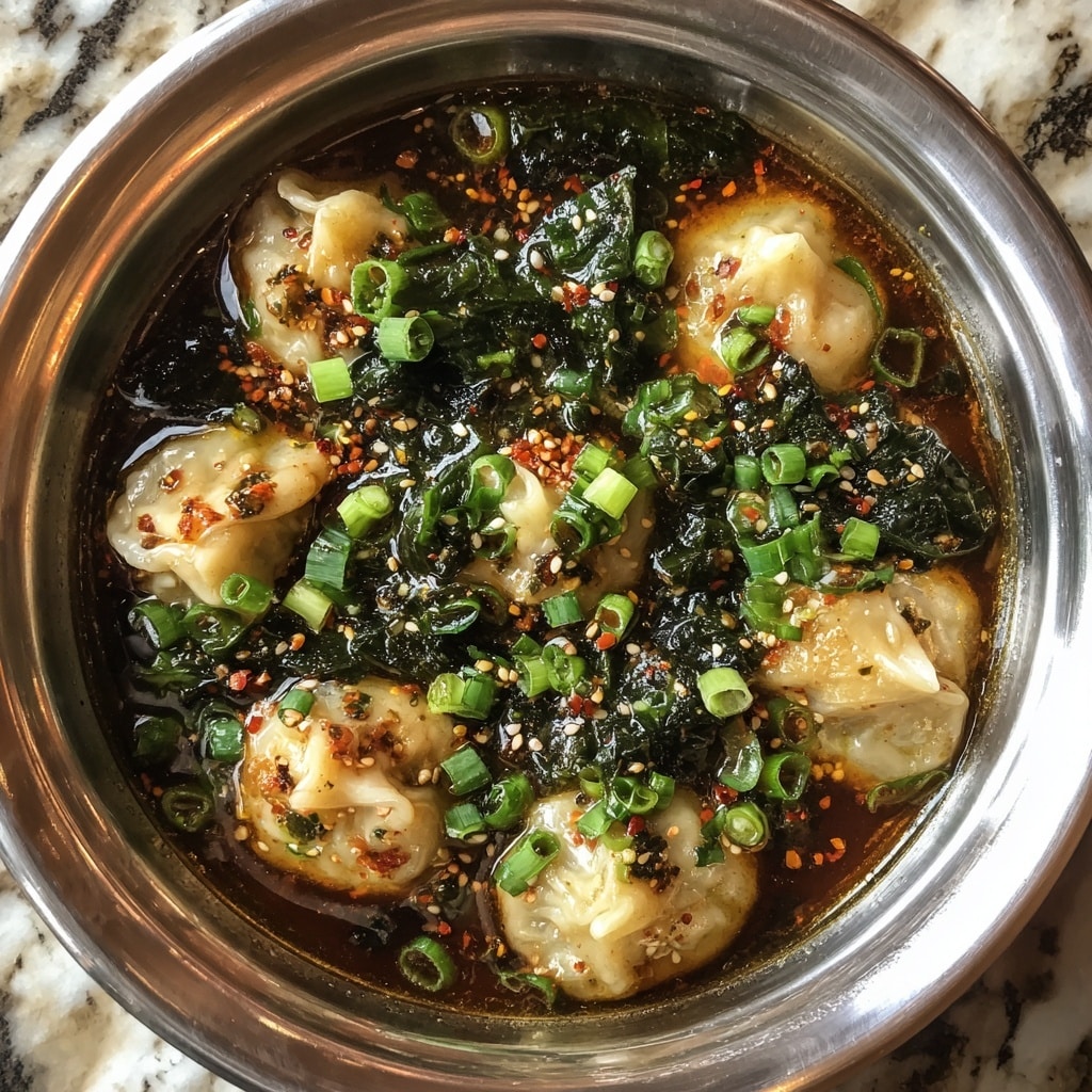 A close-up view of a metal bowl filled with light beige dumplings in a dark brown broth, topped with bright green chopped spring onions and dark green leafy vegetables, sprinkled with white sesame seeds and red pepper flakes, showing a mix of smooth and crinkled textures on the dumpling wrappers, all presented on a white marbled surface. photo taken with an iphone --ar 4:5 --v 7