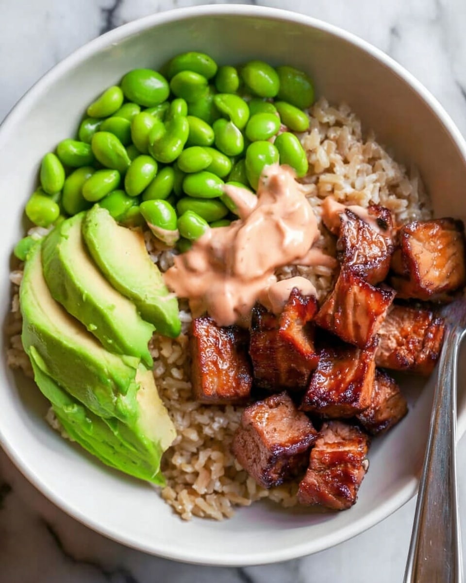 A white bowl holds a colorful layered dish starting with a base layer of light brown rice. On one side, there are bright green edamame beans piled up, next to thin, pale green slices of avocado arranged neatly. Dark brown, glossy cubes of cooked tofu with slightly charred edges are stacked on the opposite side. A creamy light pink sauce is drizzled unevenly over the tofu, edamame, and avocado. A silver fork rests inside the bowl, positioned near the tofu. The bowl is placed on a warm wooden surface with a white marbled texture beneath it. photo taken with an iphone --ar 4:5 --v 7