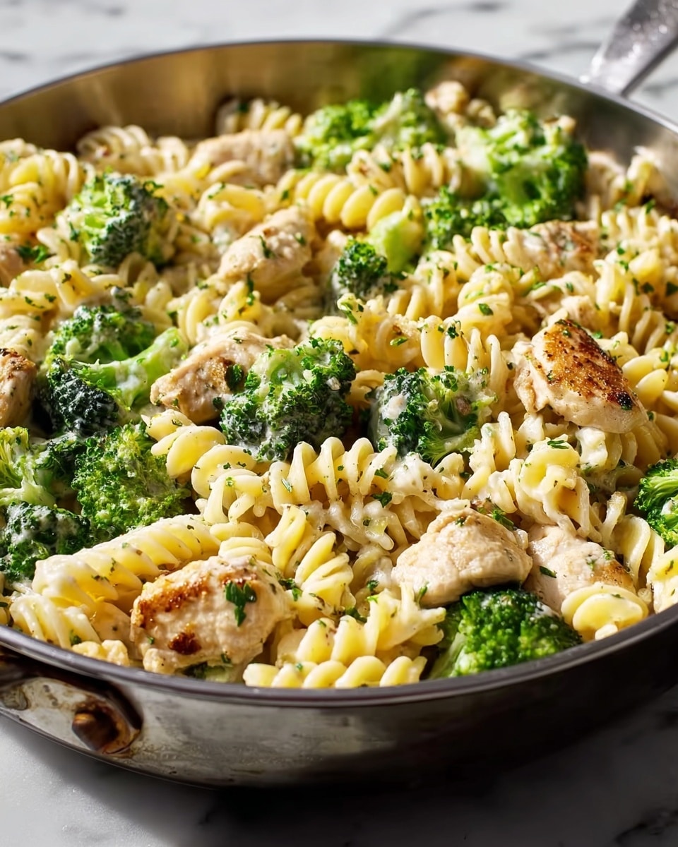 A close-up view of a stainless steel pot filled with spiral pasta and bright green broccoli florets cooking together in bubbling light golden broth. The pasta spirals are thick and roughly evenly distributed, with the broccoli pieces spread across the top and mixed in. A wooden spoon rests inside the pot, partially submerged, stirring the ingredients. Steam rises softly from the pot, which sits on a white marbled surface. photo taken with an iphone --ar 4:5 --v 7